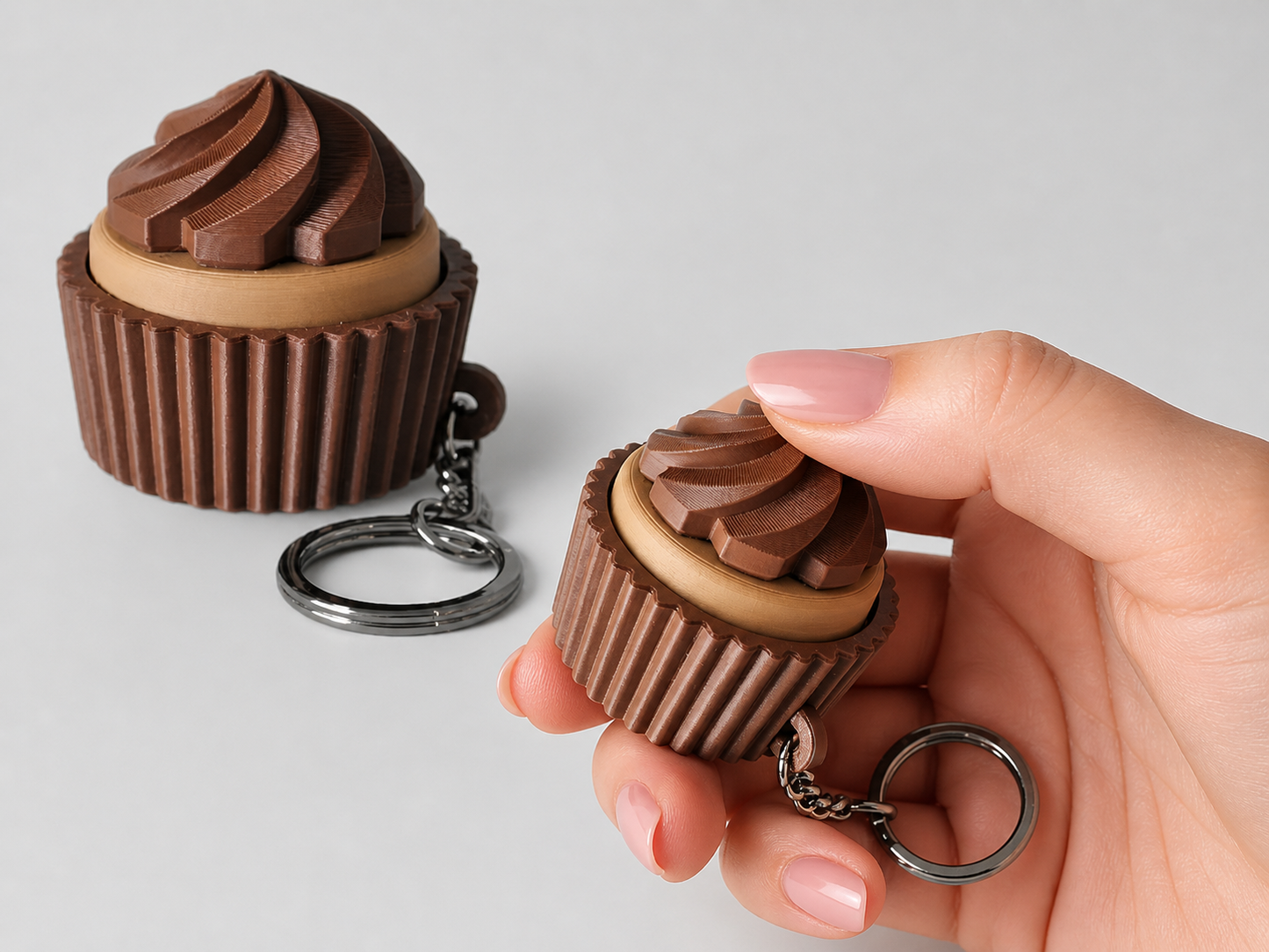 Chocolate cupcake-shaped keychain held by a hand against a light gray background
