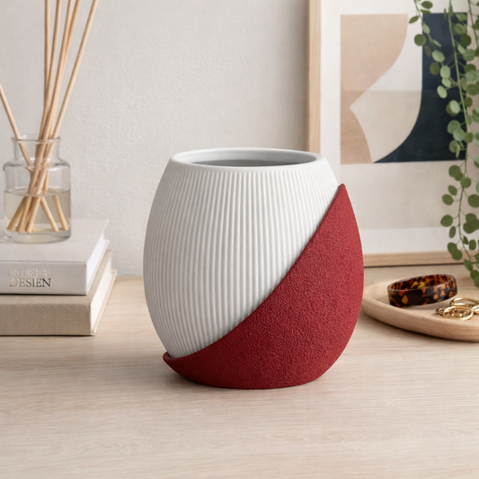 Two-toned ceramic vase on a wooden surface with decor items in the background