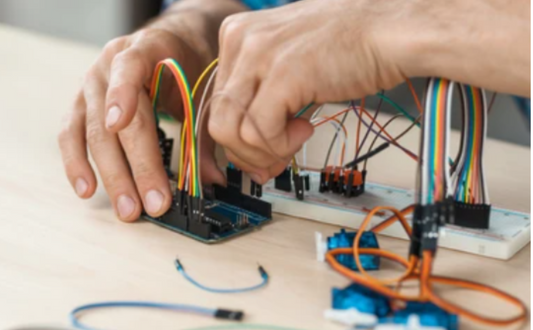 Person working with electronic components and wiring on a table