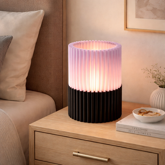 Table lamp with pink and black design on a wooden nightstand in a bedroom setting.