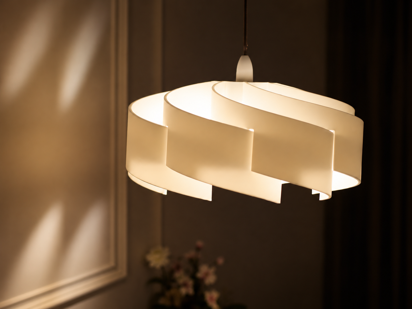 Modern pendant light fixture with a white shade in a dimly lit room.