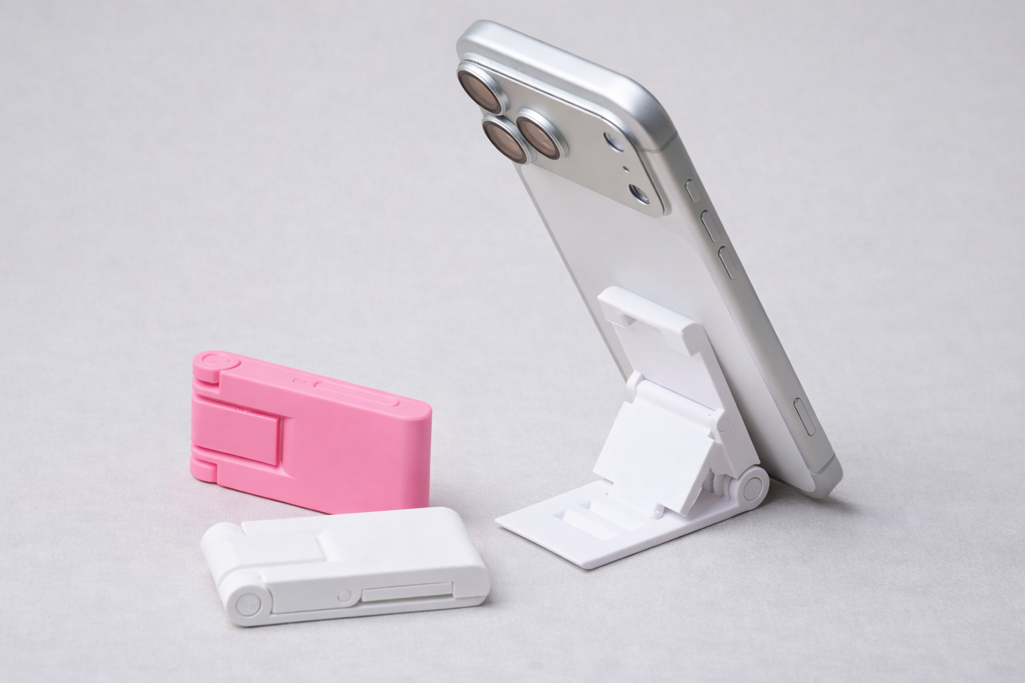 Phone stand with pink and white accessories on a light gray background