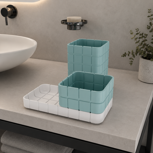 A bathroom countertop organizer set with two square grid containers in light aqua and a white tray, styled on a beige stone counter next to a white vessel sink.