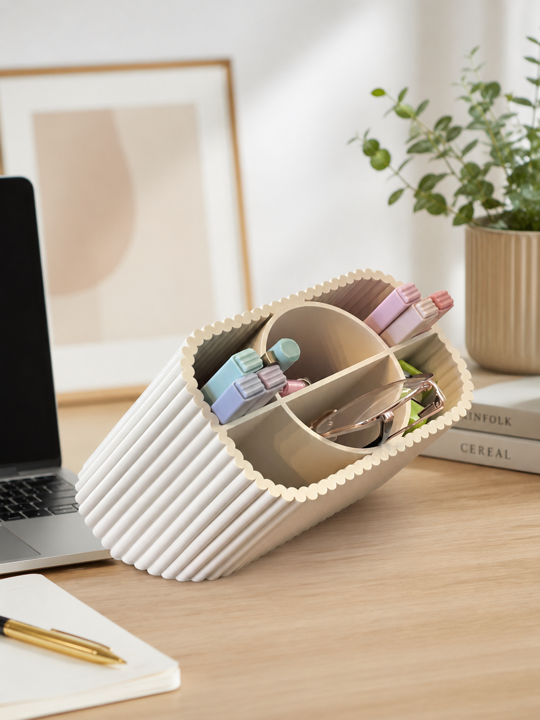 A ribbed, multi-compartment desk organizer holding pens, glasses, and small stationery items, styled on a wooden desk with a laptop, notebook, and potted plant in a bright home office setting.