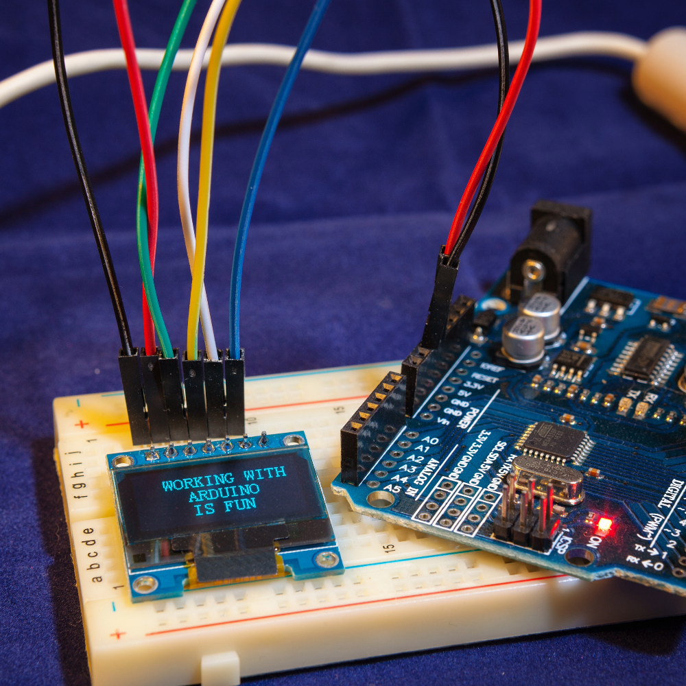 Electronic circuit board with Arduino microcontroller and LED on a blue background