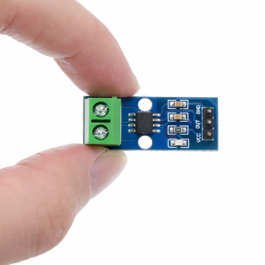 Small electronic module held between two fingers on a white background