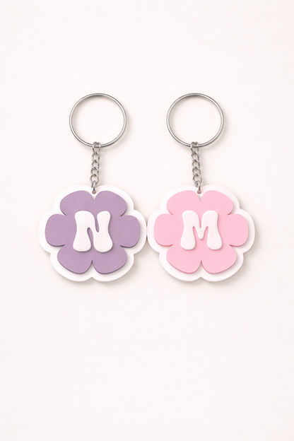 Two flower-shaped keychains with 'N' and 'M' on a white background