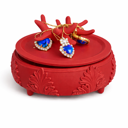 Red jewelry box with heart-shaped blue gemstone earrings on a white background