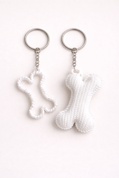 Two white keychains shaped like a sock and a bone on a white background