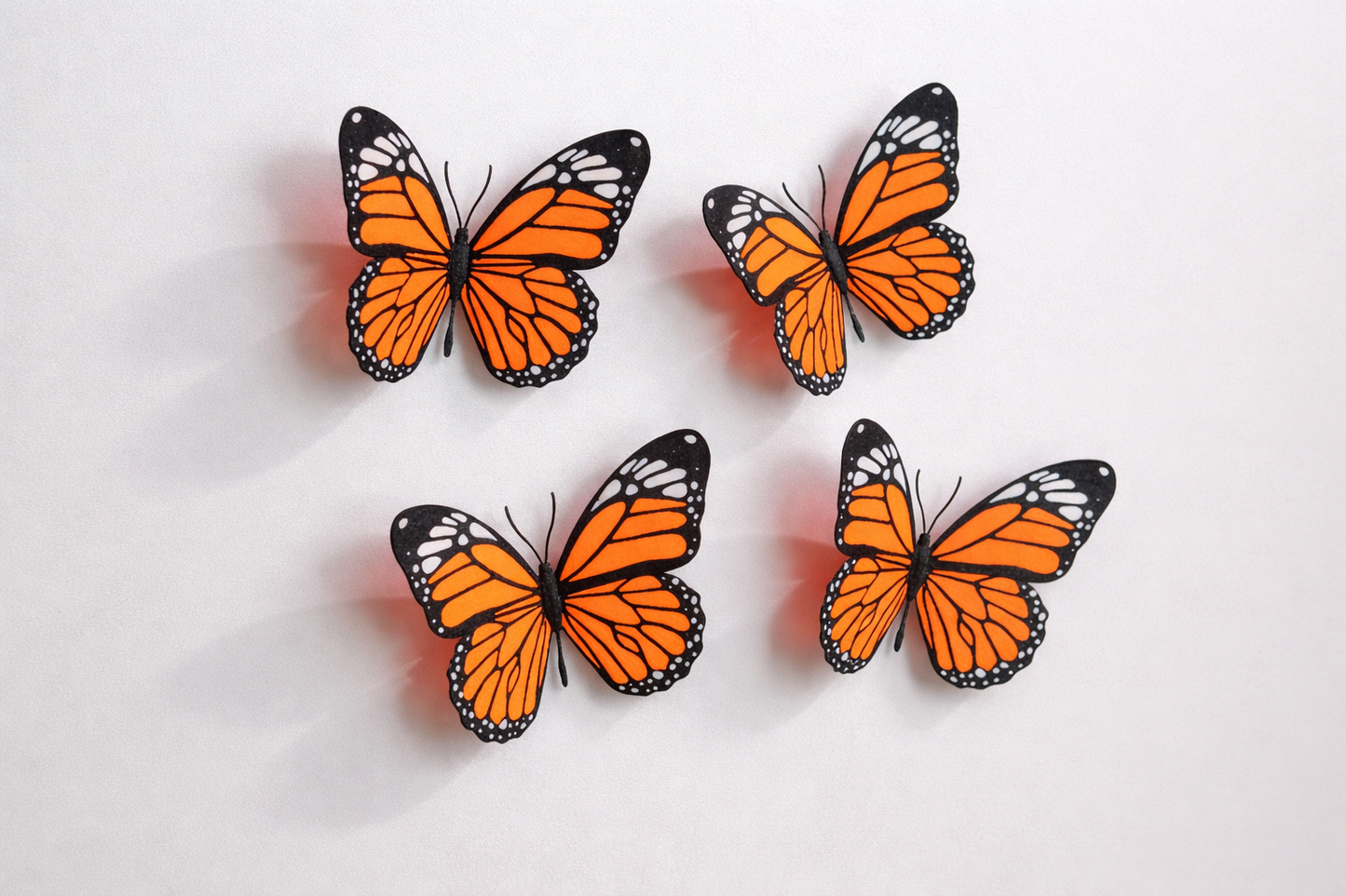Four orange butterflies with black spots on a light gray background