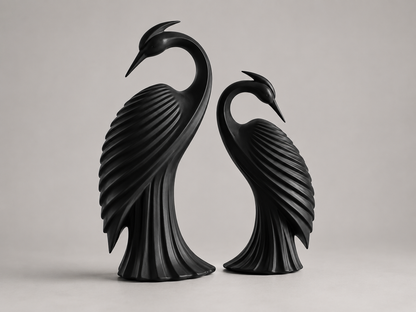 Two black heron bird sculptures standing side by side on a light gray studio background.