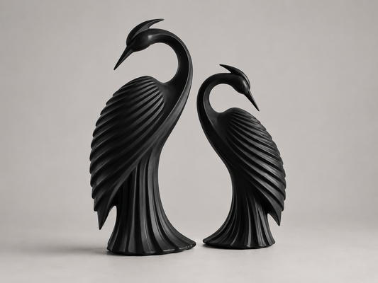 Two black heron bird sculptures standing side by side on a light gray studio background.
