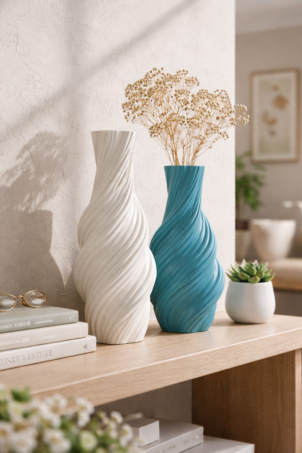 Two vases, one white and one blue, on a wooden surface with books and a plant in the background.