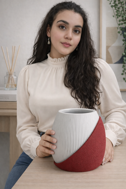 Woman holding a ceramic vase with a white top and red bottom in a home setting.