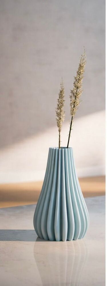 Striped vase with gold leaves on a reflective surface