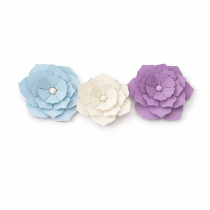 Three paper flowers in blue, white, and purple on a white background