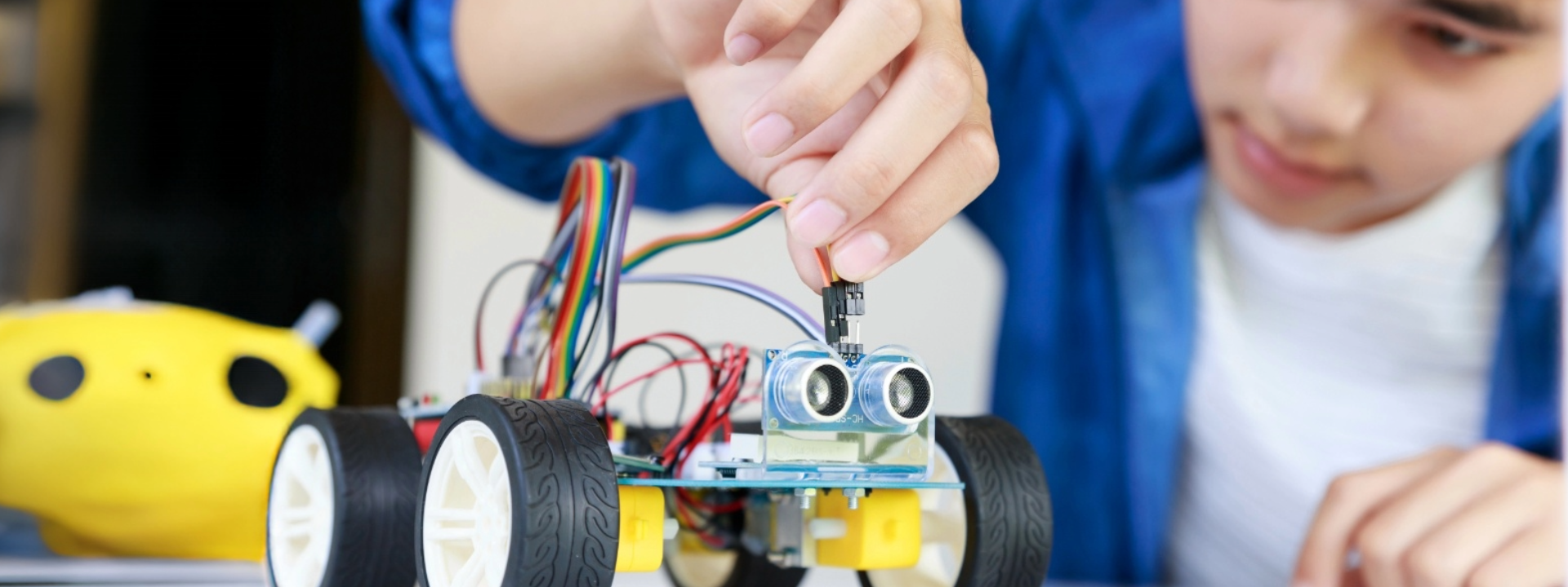 Child assembling a small robot with electronic components