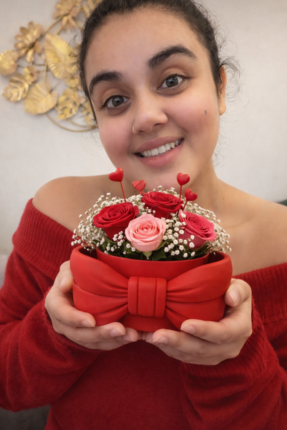 Woman holding a red gift box with flowers against a neutral background