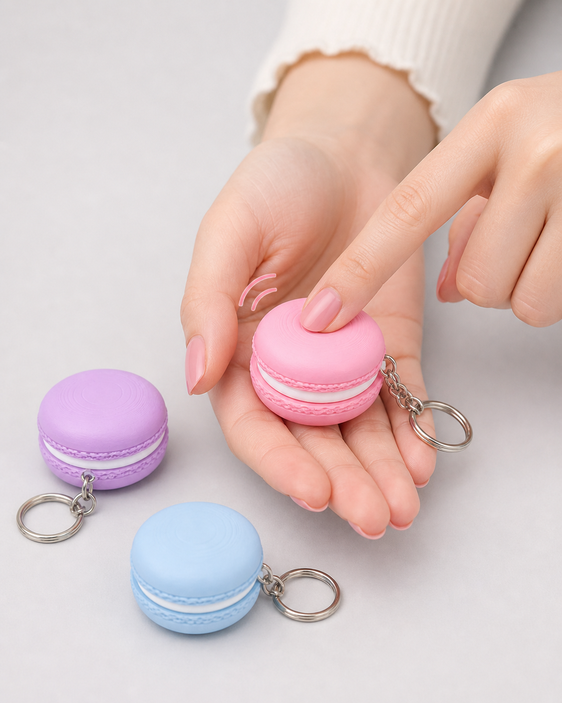 Hand pressing pastel macaron clicker keychain to show the satisfying clicker function