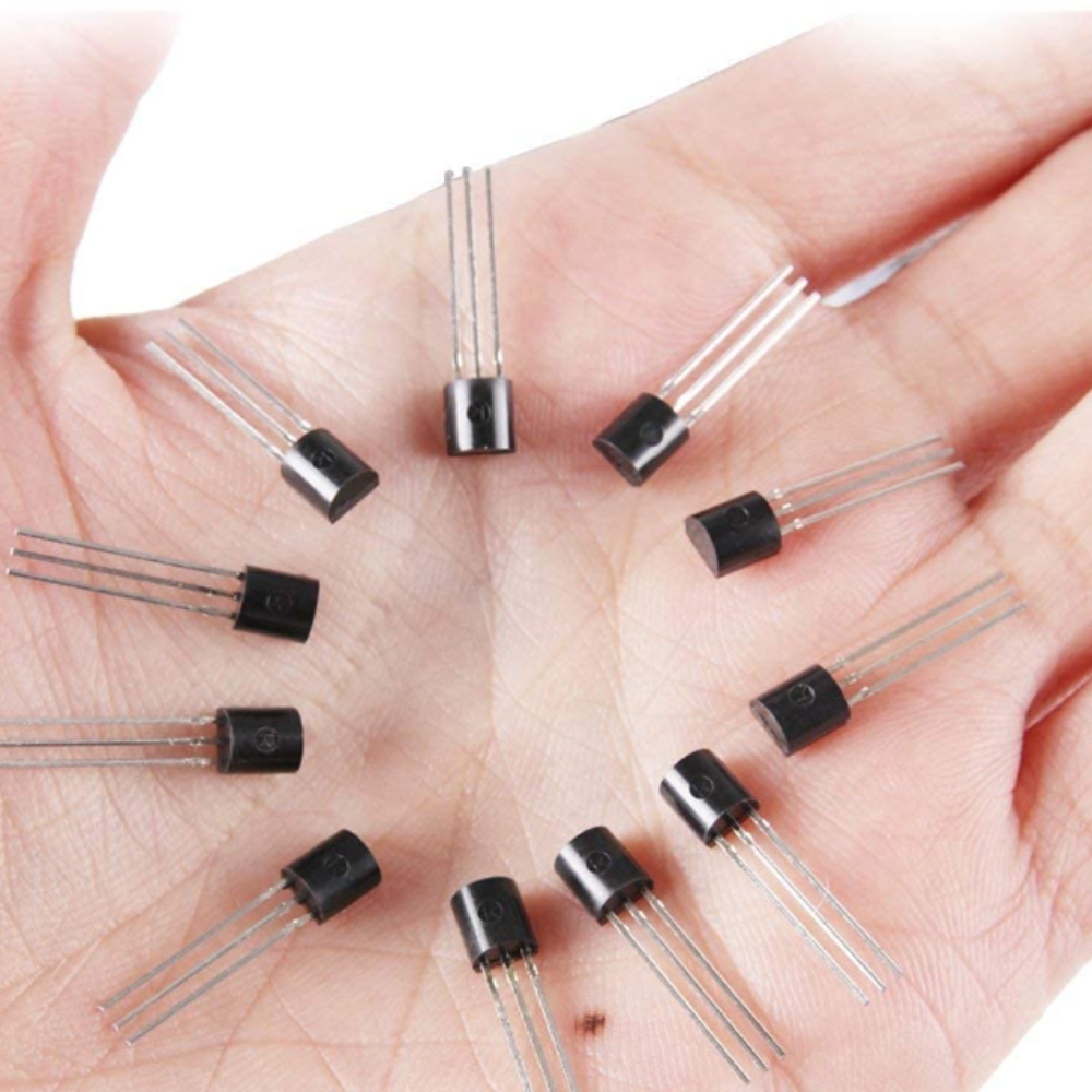 Hand holding multiple transistors on a white background
