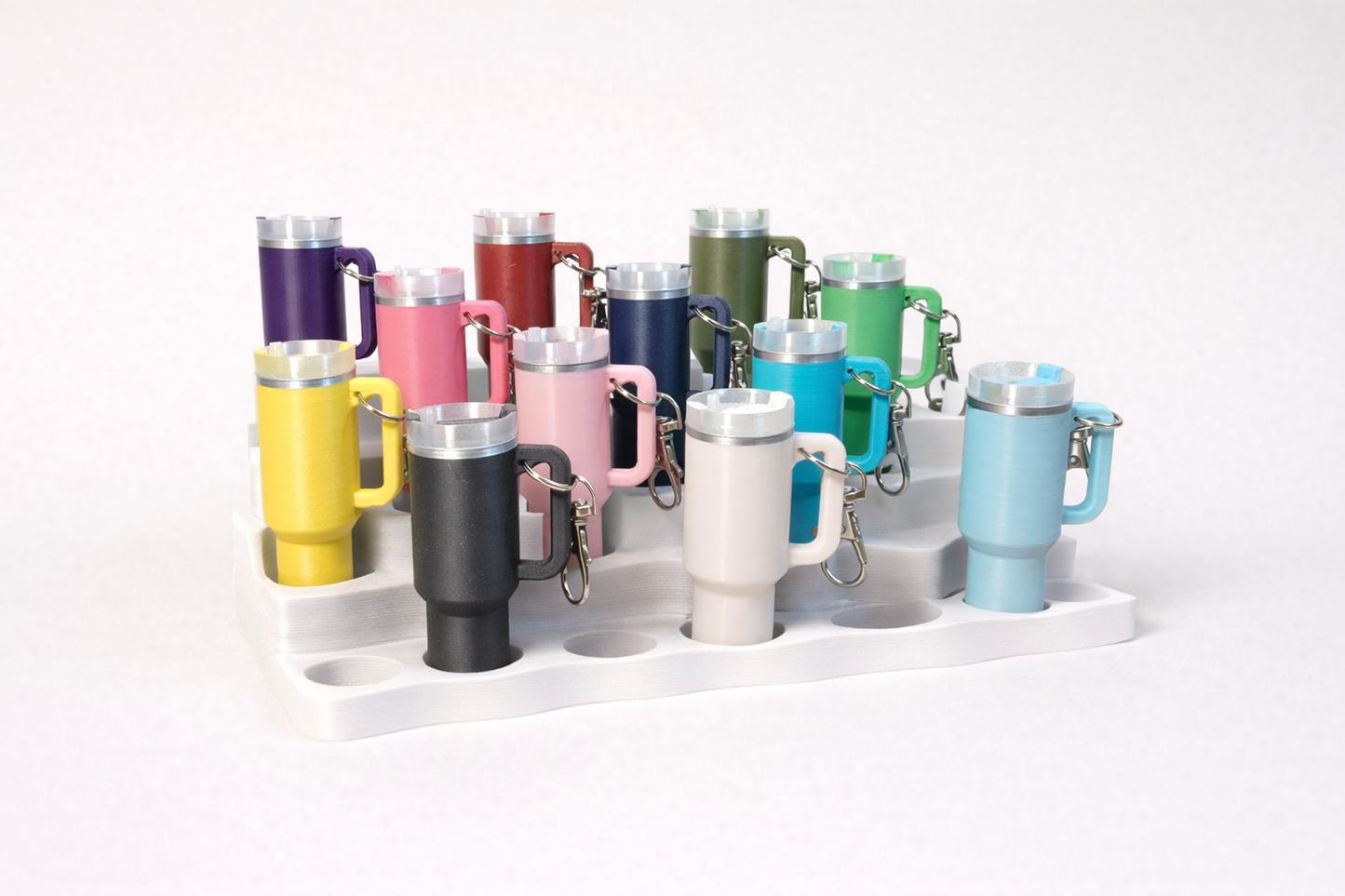 Collection of colorful insulated mugs with keychains on a white background