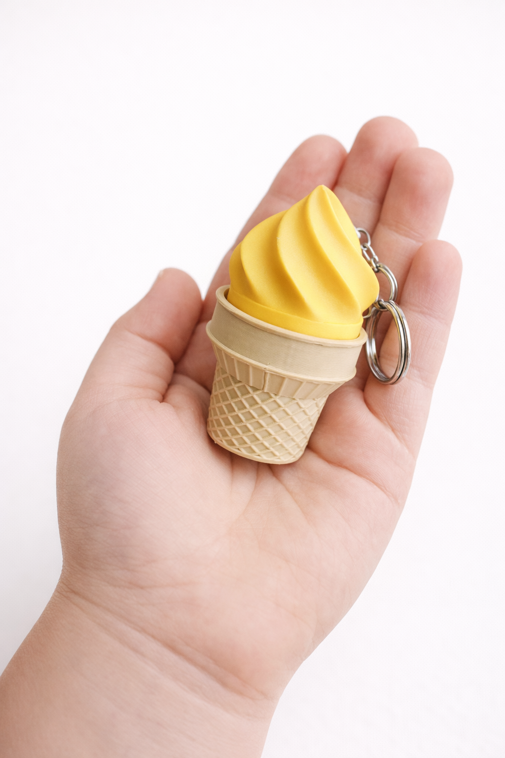 Ice cream cone keychain held in a hand against a white background