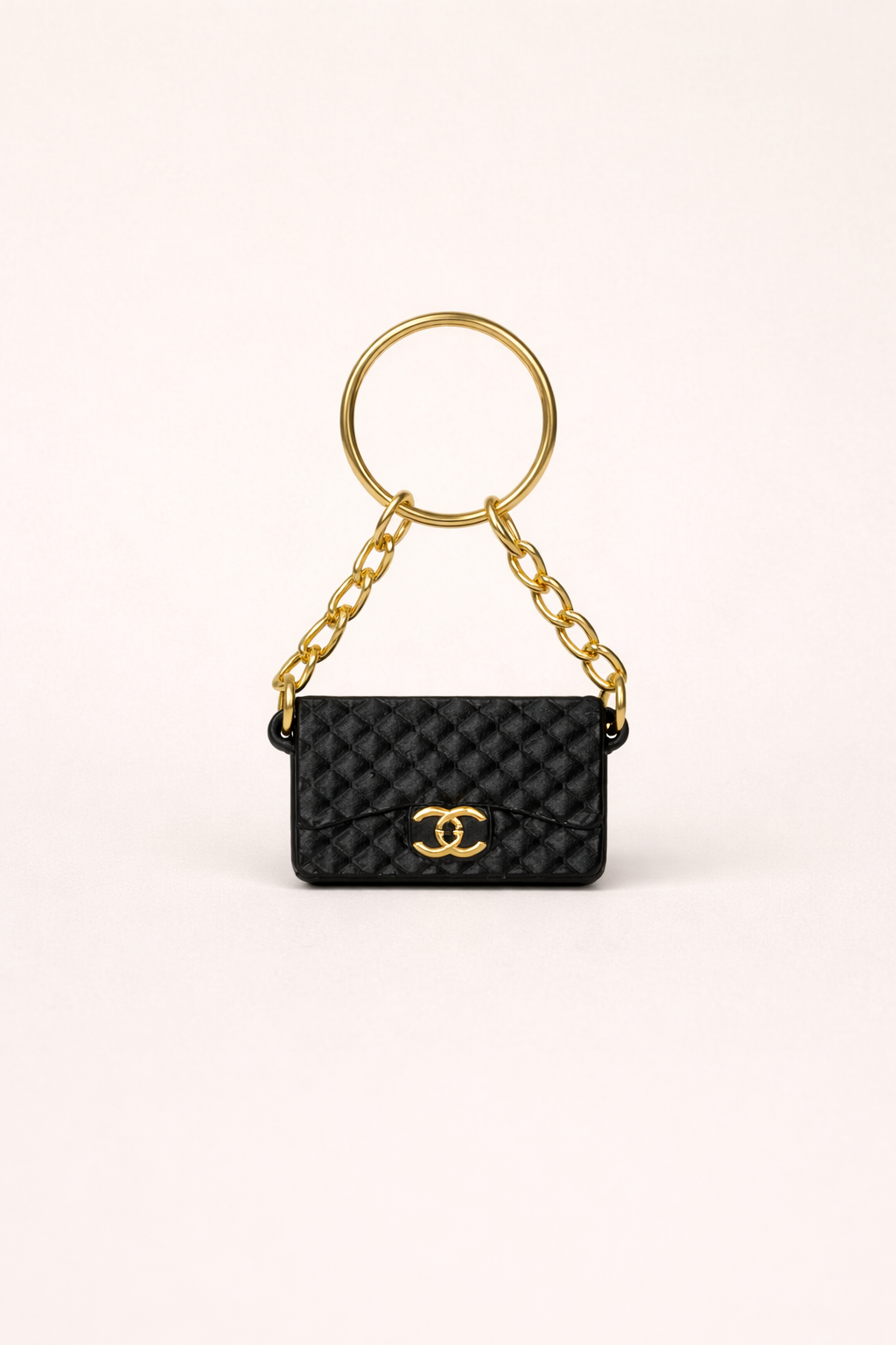 Black quilted handbag keychain with gold chain and clasp on a white background