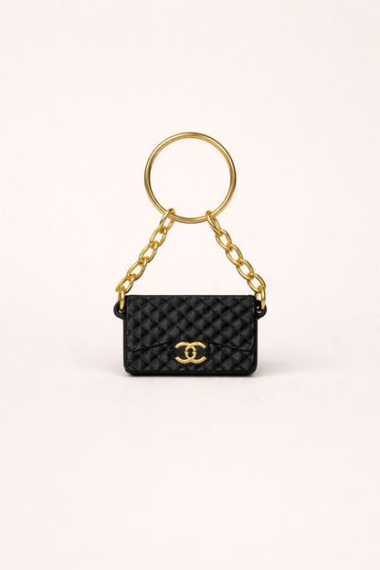 Black quilted handbag keychain with gold chain and clasp on a white background