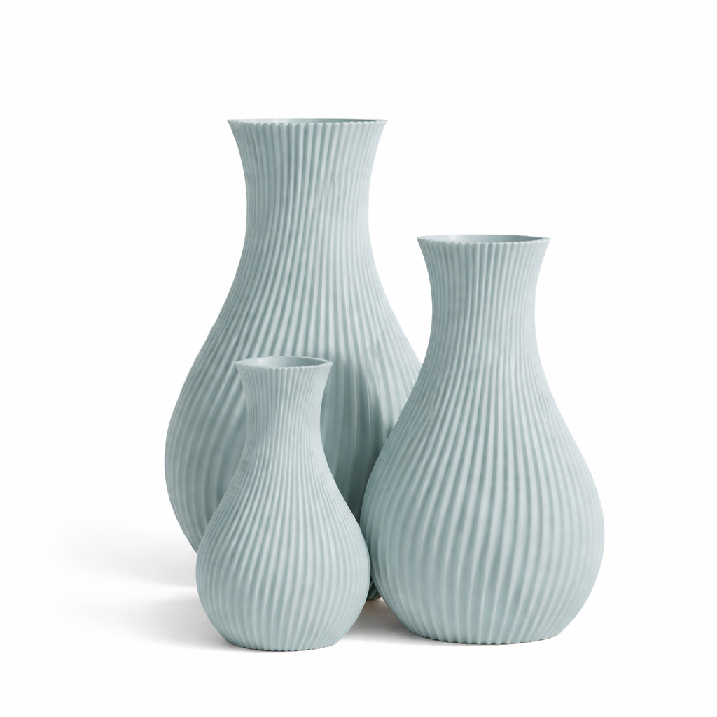 Set of three light blue ribbed vases on a white background