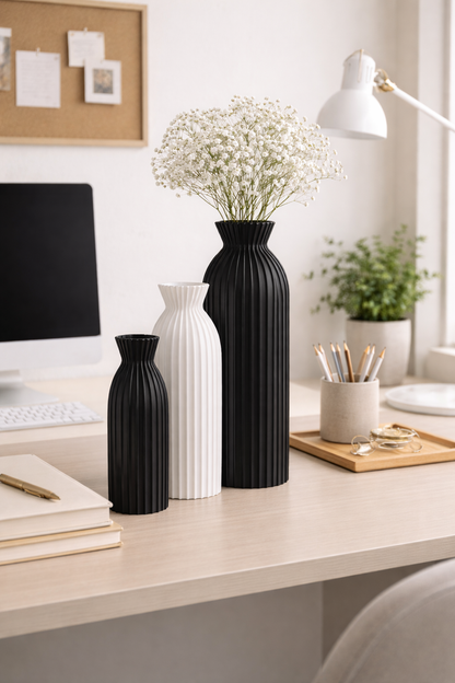 Black and white vases on a desk with a computer and office supplies in the background.