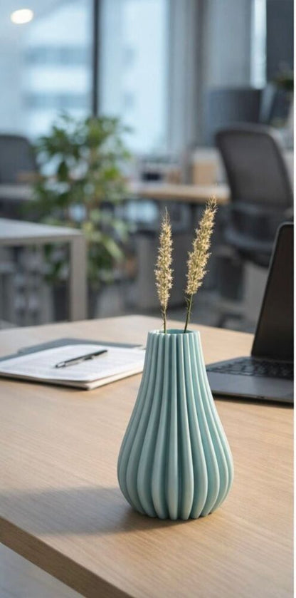 Teal ribbed vase with dried plants on a desk in an office setting