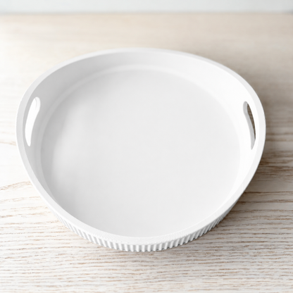 A white ceramic serving tray with two side cutouts, shown on a light wood surface.
