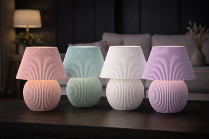 Four table lamps with ribbed design and pastel colors on a dark surface.