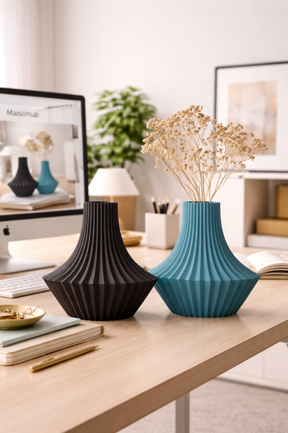 Two decorative vases, one black and one blue, on a table with a computer monitor in the background.