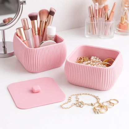 Pink ribbed jewelry box with makeup brushes and accessories on a white surface