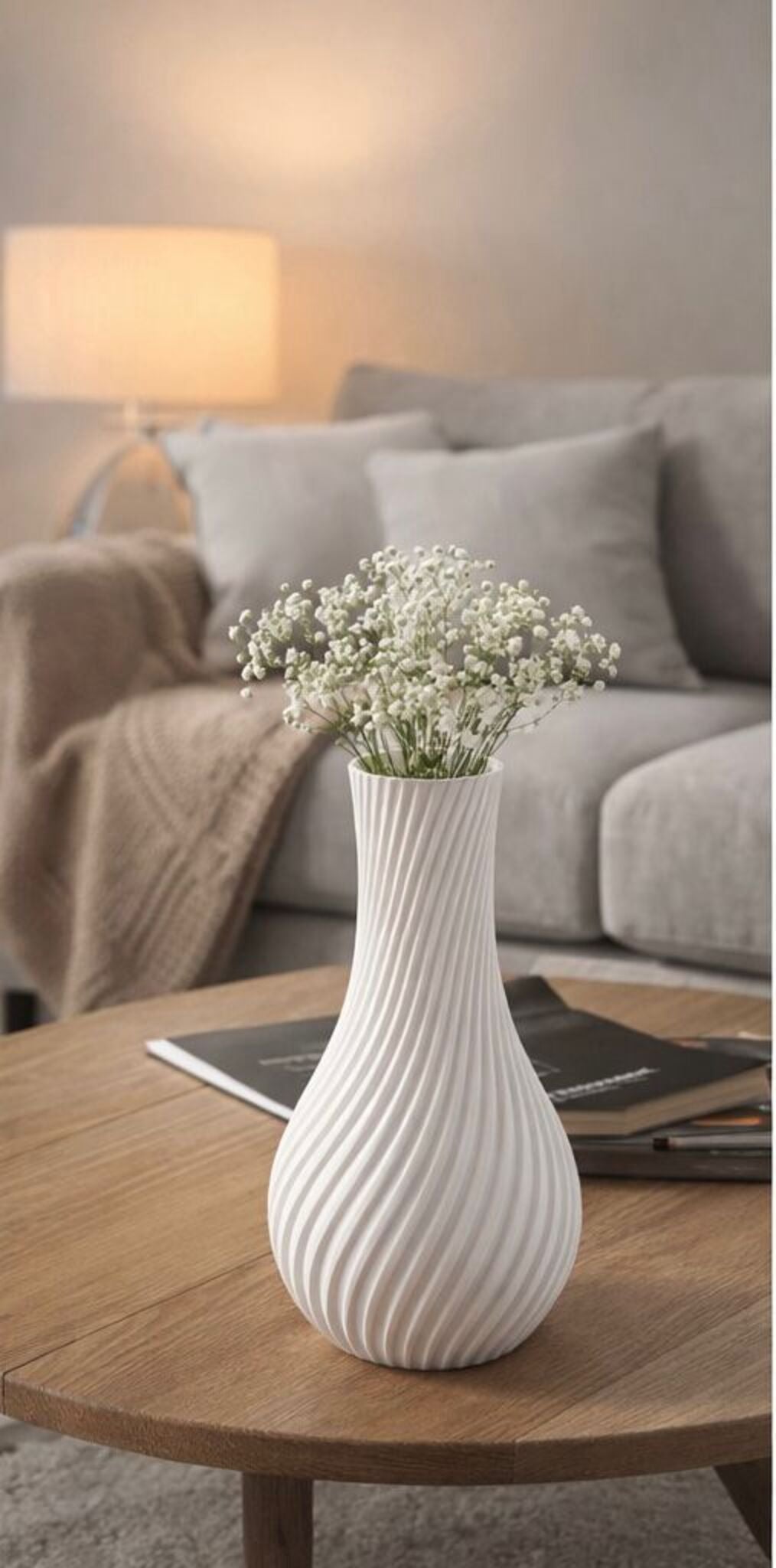 White textured vase with baby's breath on a wooden table in a cozy living room.