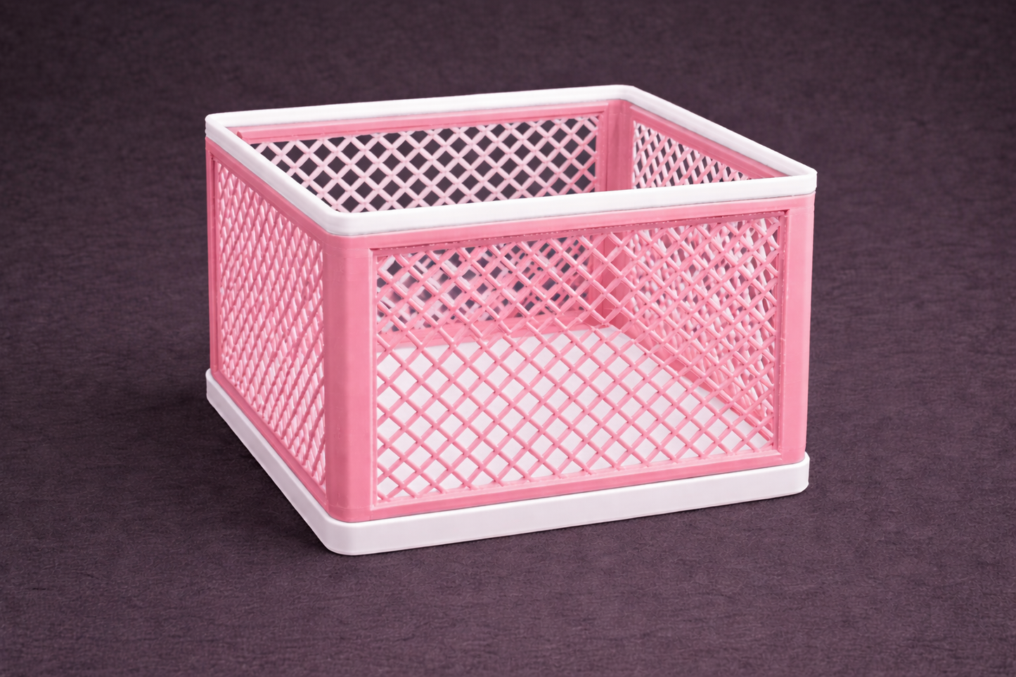 Pink and white woven storage basket on a dark background