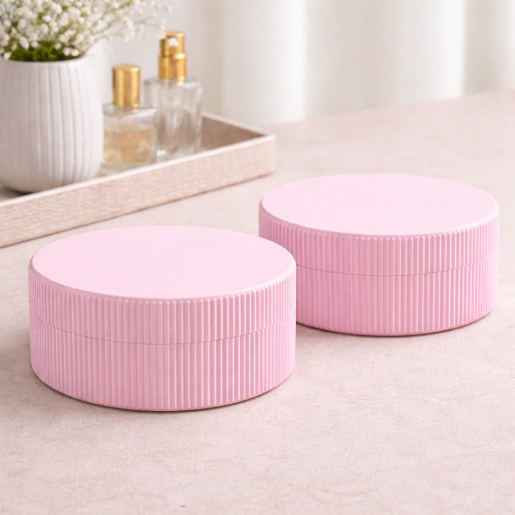 Two pink cylindrical containers on a light surface with a blurred background