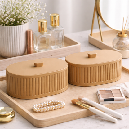 Two beige ceramic containers on a wooden tray with makeup items in the background.