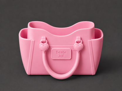 A pink silicone handbag-shaped container with heart-shaped handles and a central embossed label reading 'Beste Juf', shown on a dark gray background.