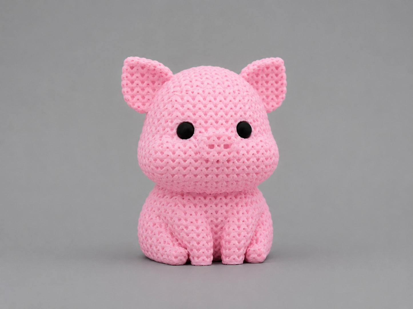 Pink knitted pig toy on a gray background