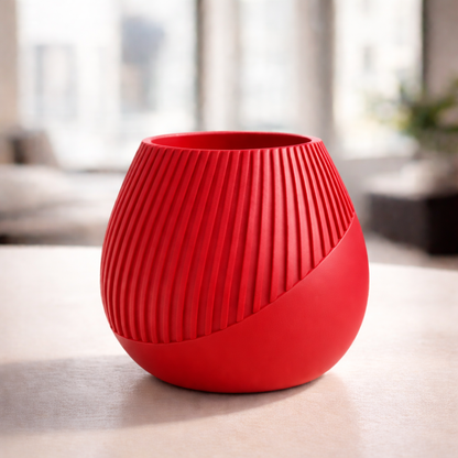 Red textured vase on a light surface with a blurred indoor background