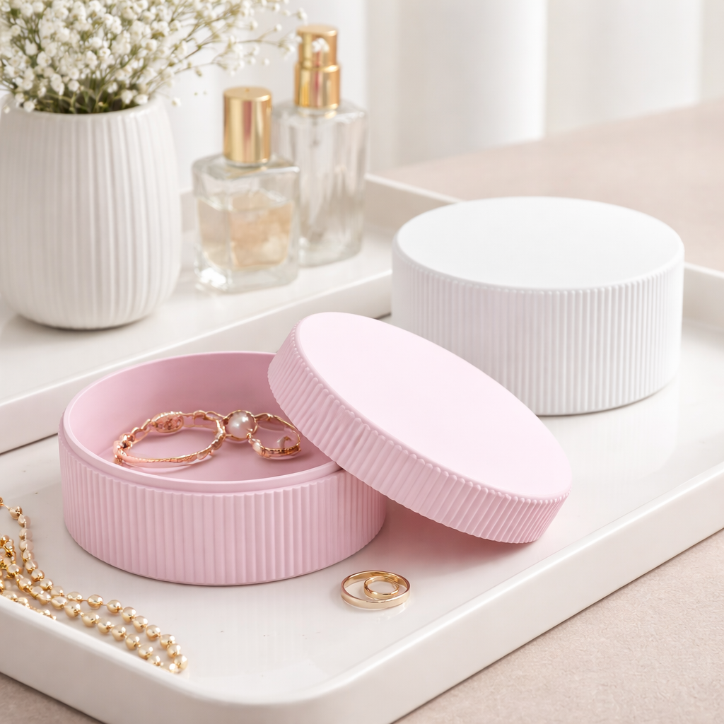 Pink jewelry box with gold jewelry on a white surface with a blurred background