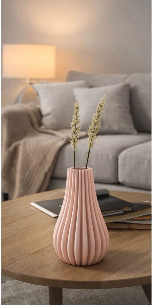 Pink vase with dried plants on a wooden table in a cozy living room.
