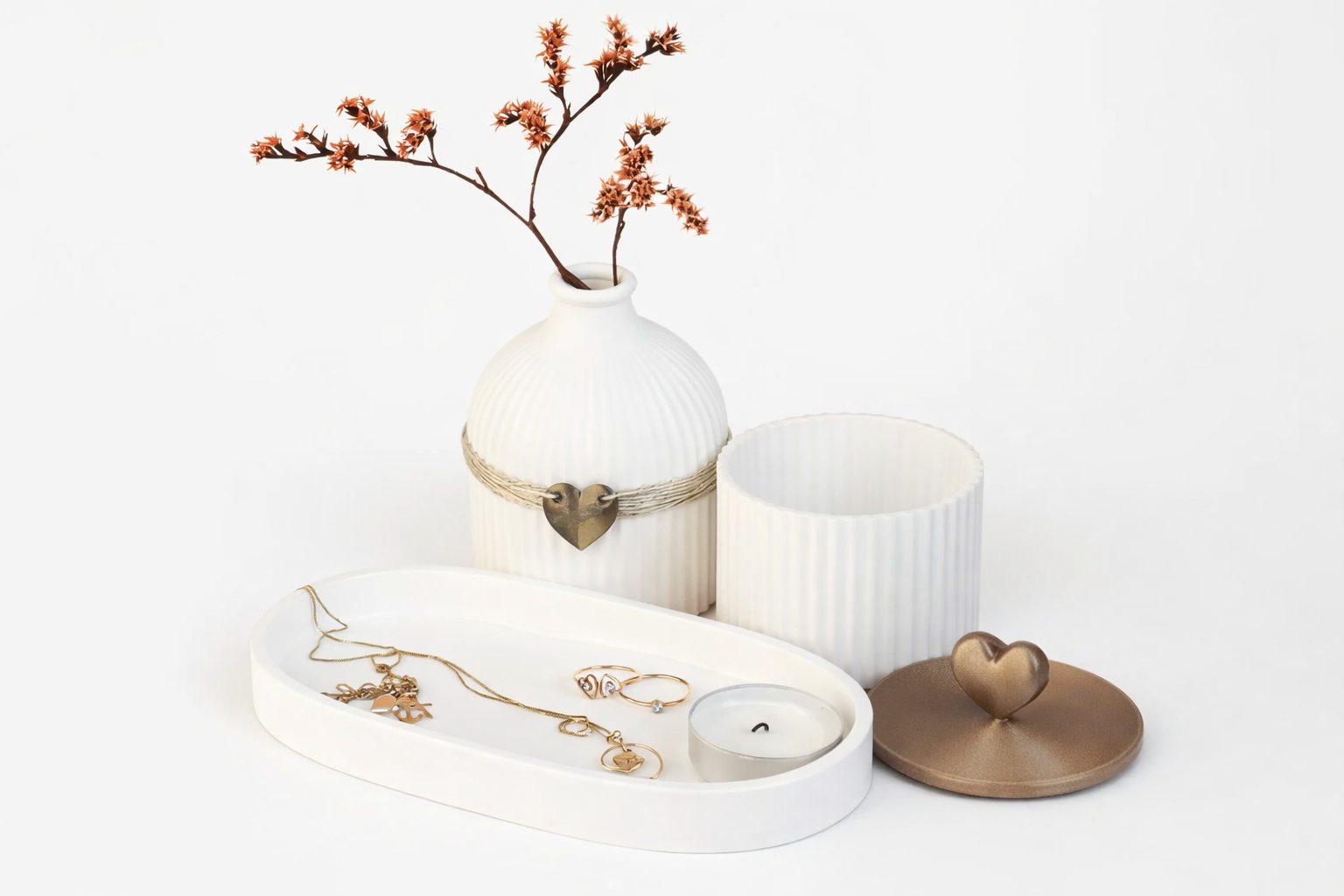 Decorative setting with a vase, candles, and jewelry on a white surface