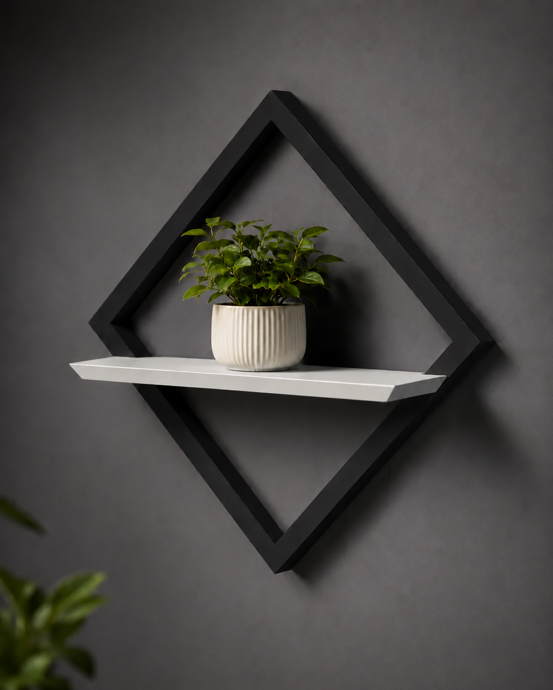 Black geometric wall shelf with a white base holding a potted plant against a dark gray wall.