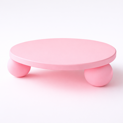 Pink round stool with three small legs on a white background