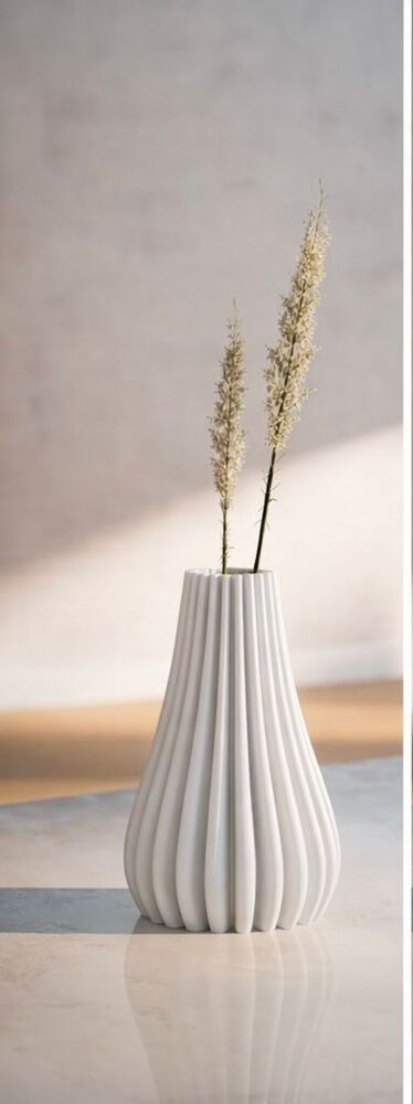 White textured vase with a single plant on a light gray surface