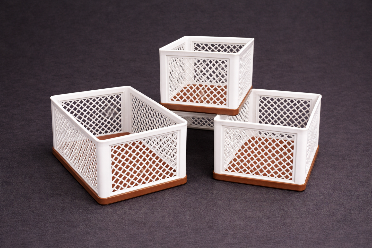 Three white woven storage baskets with brown wooden bases on a dark background