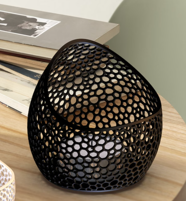 Black decorative lantern with a honeycomb pattern on a wooden surface.